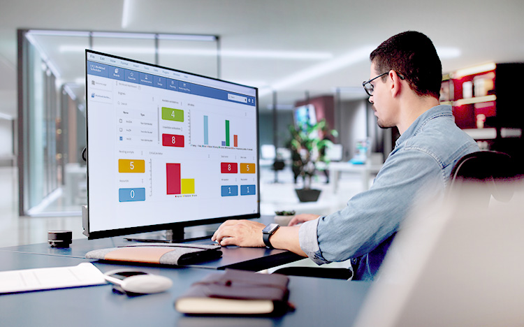 Business professional analyzing HCL Workload Automation SAP integration dashboard with colorful data metrics