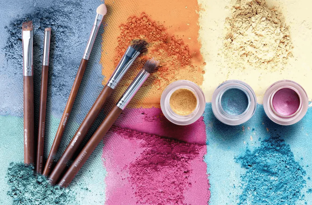Assorted colorful powdered eyeshadows with makeup brushes and small containers